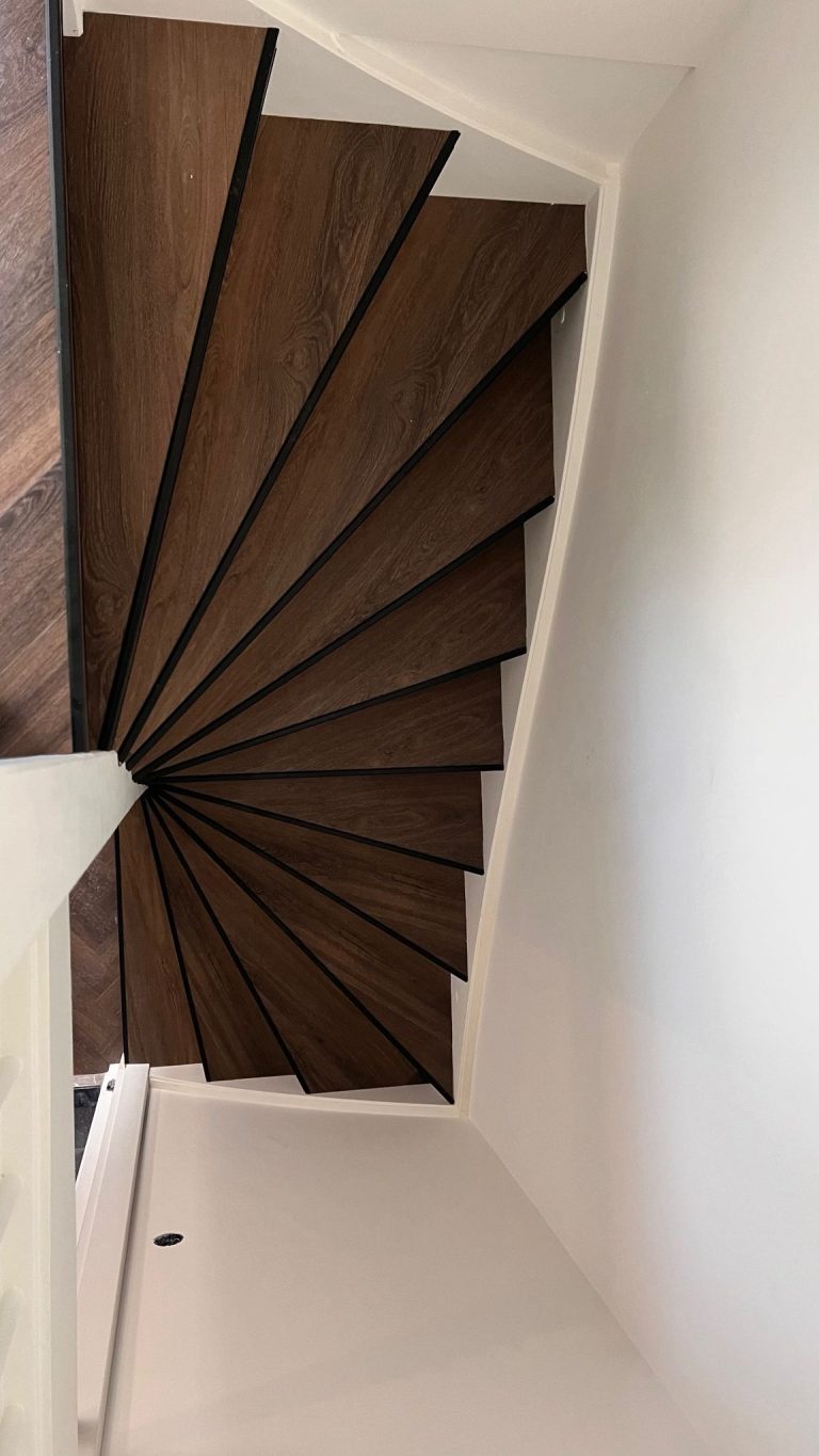 Spiltrap in donkere houtlook langs een witte wand