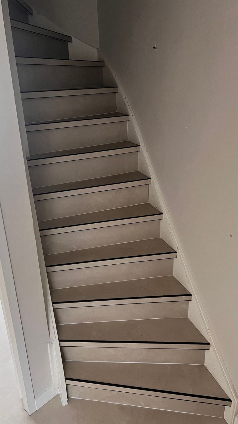 Lichte trap met donkere stootrand in een hal